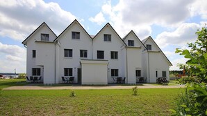 A large, white, multi-story building with a symmetrical facade, multiple windows, and outdoor seating areas. - Appartement Hafenflair am Plauer See (Plau am See)
