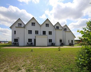 Ein großes, weißes, mehrgeschossiges Gebäude mit symmetrischer Fassade, zahlreichen Fenstern und Außenbereichen zum Sitzen.