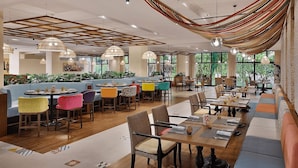 Ein geräumiges Restaurant mit verschiedenen Sitzbereichen, darunter Sitzecken und Tische, und großen Fenstern, die für natürliches Licht sorgen.