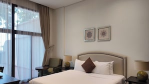 Ein Hotelzimmer mit einem großen Bett, Nachttischen, einem Schreibtisch und einem Sessel.