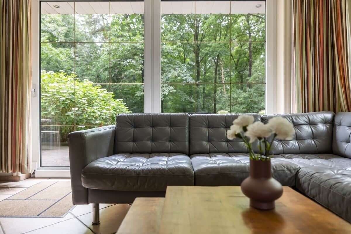 Een moderne woonkamer met een leren bank, een houten salontafel en een vaas met bloemen.