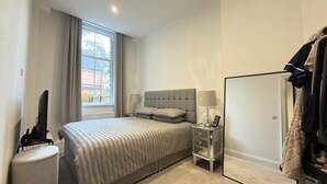 Ein Schlafzimmer mit Bett, Nachttisch, Lampe und Kleiderschrank.