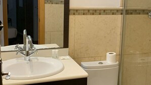 A bathroom with a sink, mirror, toilet, and glass shower enclosure. - Madrid Hideaway Near Museums (Madrid)