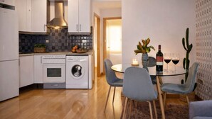 A modern kitchen with a washing machine, a dining area with a glass table and chairs, and a cactus plant. - Madrid Hideaway Near Museums (Madrid)
