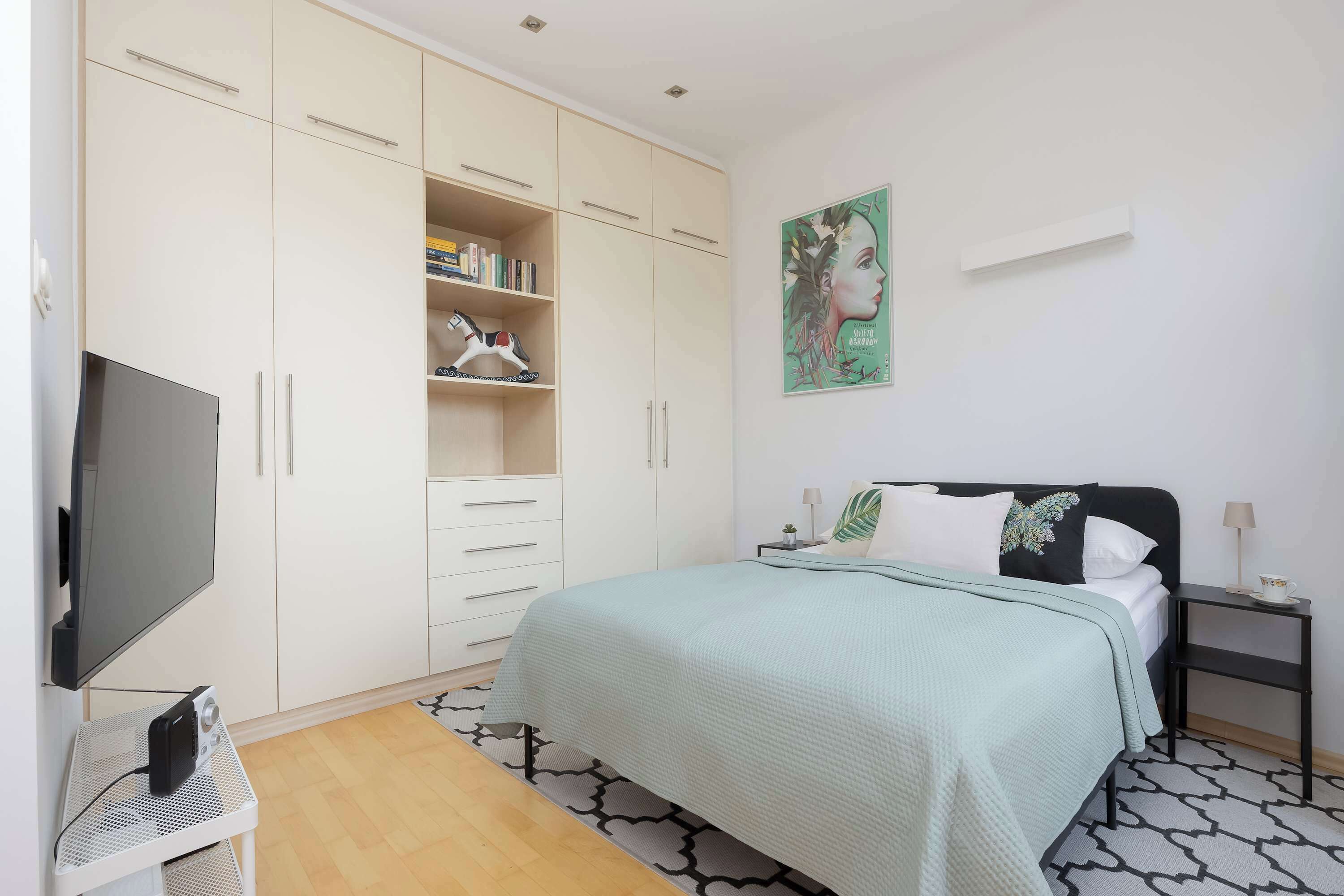 Ein Schlafzimmer mit einem Bett, einem Fernseher, einem Kleiderschrank und einem Bild an der Wand.