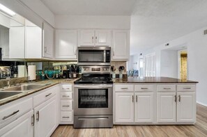 Une cuisine moderne avec des meubles blancs, des appareils en acier inoxydable et un plan de travail en granit.