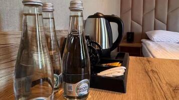 A wooden table with two bottles of water, a kettle, and a tray with a napkin.