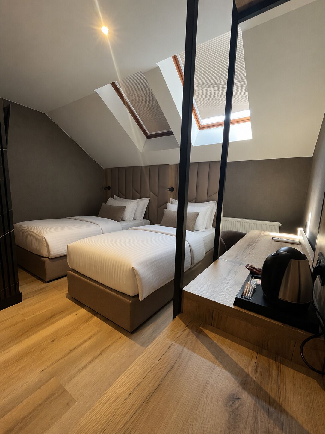 Une chambre moderne avec deux lits, une lucarne et un plancher en bois.