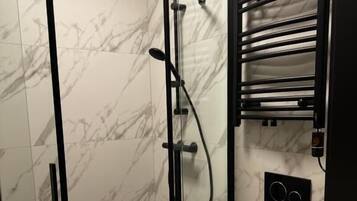 A bathroom with a glass-enclosed shower, a toilet, and a sink.