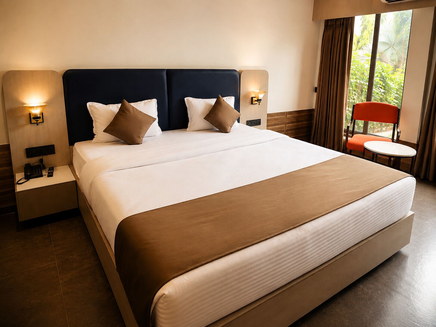 A hotel room with a large bed, two bedside tables with lamps, a small round table, and a chair.