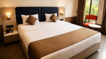 A hotel room with a large bed, two bedside tables with lamps, a small round table, and a chair.