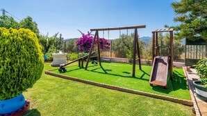 Un patio trasero con un parque infantil, tobogán y césped cuidado.