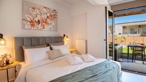 Quarto com cama, mesas de cabeceira, um quadro e vista para o exterior.