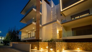 Um edifício moderno de vários andares com varandas, um muro decorativo e vasos de pedra.