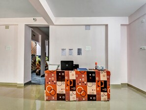 A reception desk with a laptop, a bottle, and a box. There are three notices on the wall. - Hotel O Downtown INN (Barasat)