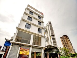 A multi-story building with a sign for Tandoori Chai Junction, featuring a large window and a covered entrance. - Hotel O Downtown INN (Barasat)