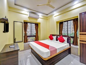 A hotel room with a bed, a desk, an air conditioner, and a window with curtains. - Hotel O Downtown INN (Barasat)