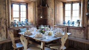 Een houten eetkamer met een grote tafel gedekt voor een maaltijd, omringd door stoelen en versierd met blauw en wit keramiek servies.