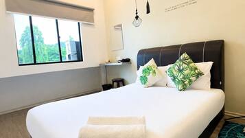A modern hotel room with a large bed, an air conditioning unit, a window with a view, and a wall with hanging lights and a motivational quote.