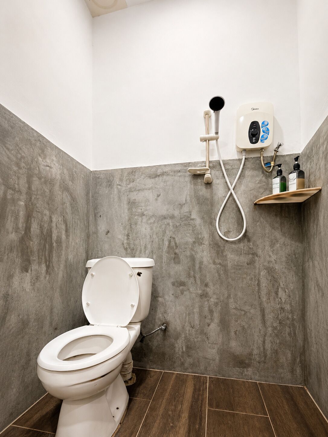 Une salle de bain équipée de toilettes, d’une douche et d’une étagère où sont rangés les articles de toilette.