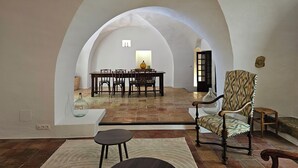 An arched room with a dining table and chairs, a patterned armchair, and a small table with a vase. - Beautiful Village House (Lauris)