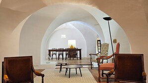 A spacious room with a high arched ceiling, a dining area with a table and chairs, and two armchairs. - Beautiful Village House (Lauris)