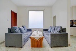 Una sala moderna con dos sofás grises, una mesa de centro de madera y un amplio ventanal.