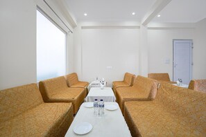 Habitació d'hotel amb una taula llarga, dos sofàs i una porta.