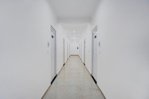 Un passadís llarg i estret amb parets i portes blanques, que condueix a un extrem llunyà.