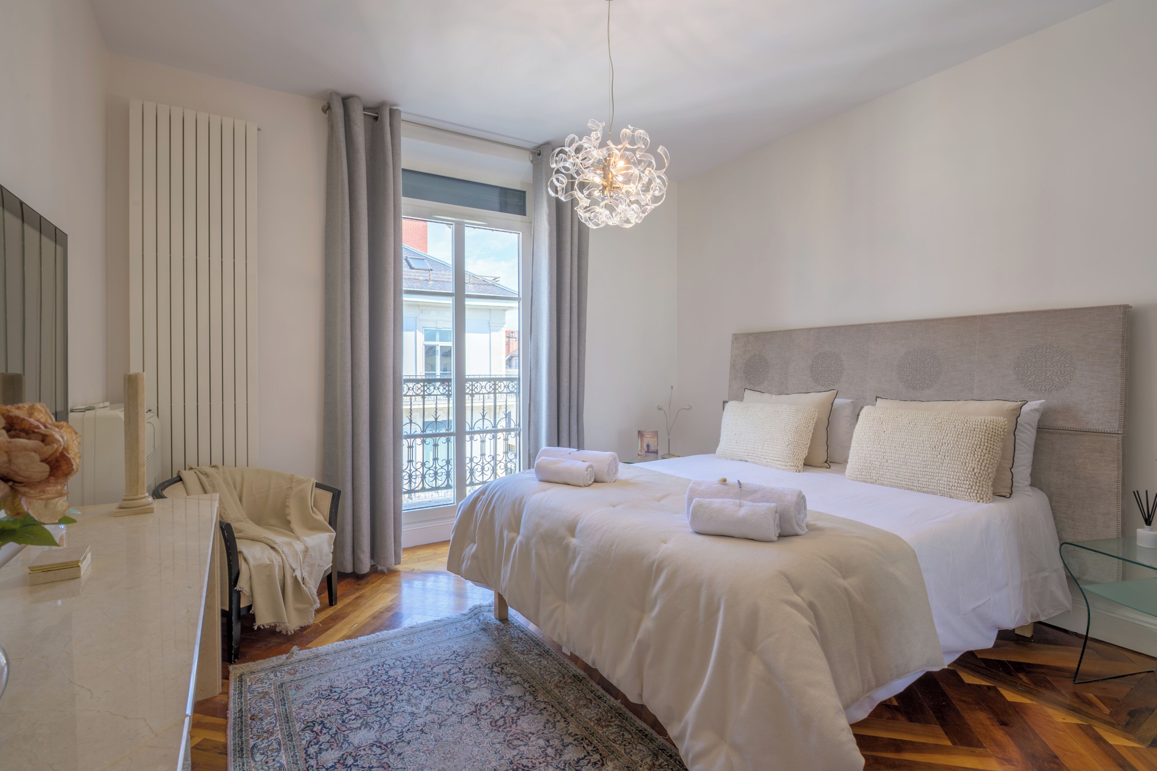 Una camera da letto con un letto grande, una lampada a sospensione, vista all'esterno e una finestra con tende.