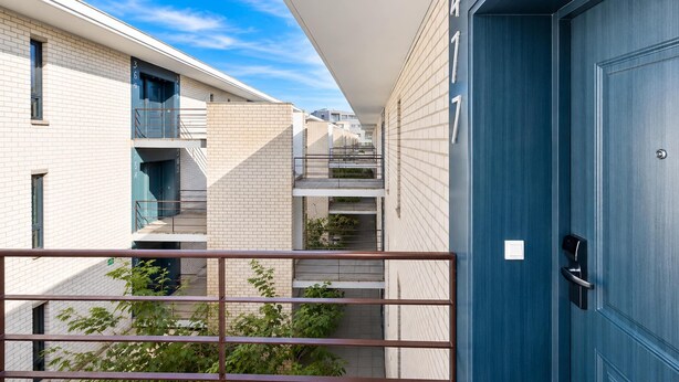 En moderne bygning med en blå dør, en balkon og en klar himmel.