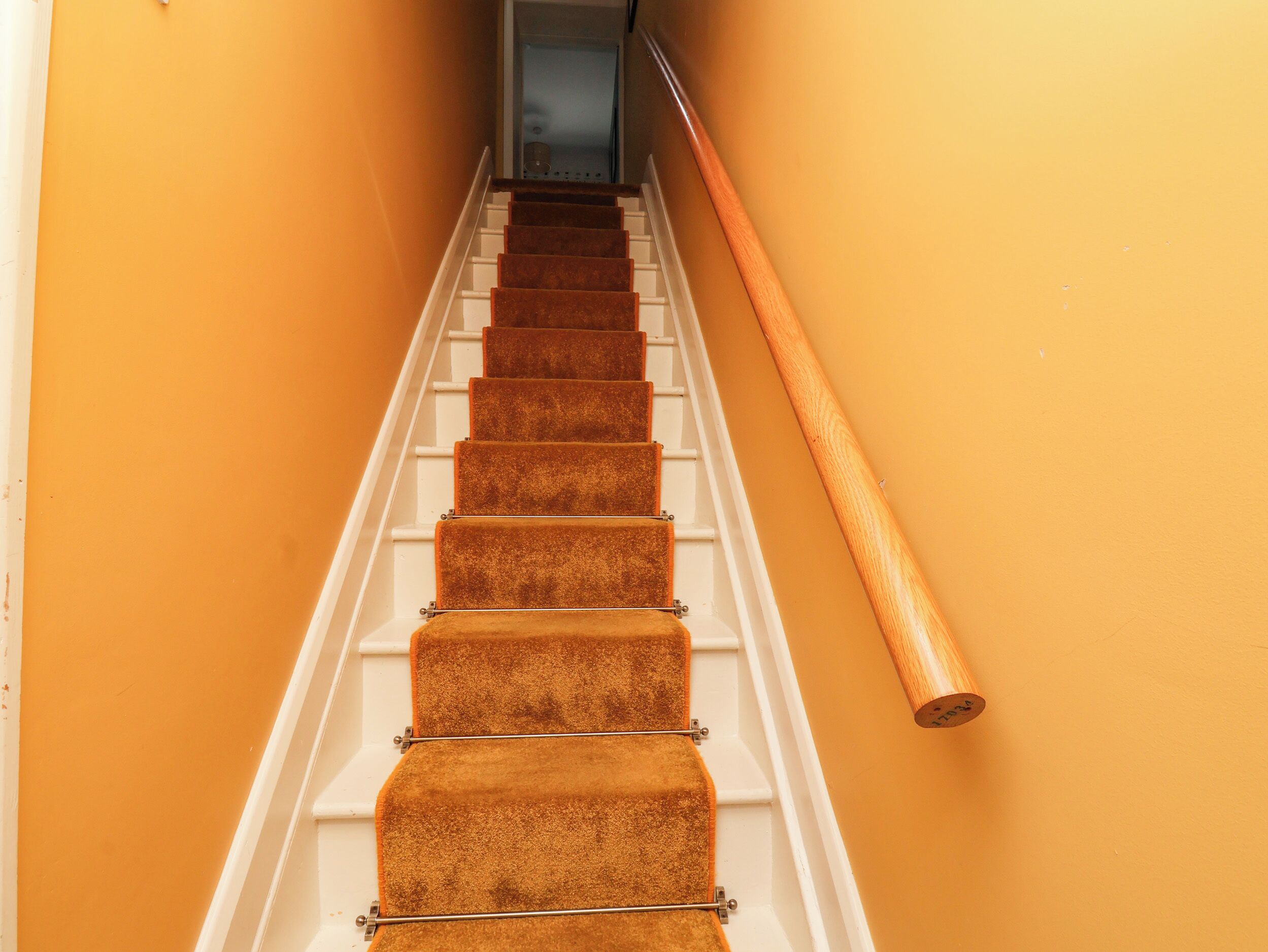 A staircase with carpeted steps and a wooden handrail.
