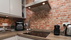 Une cuisine avec un mur en briques, un plan de travail, une machine à café et un grille-pain.