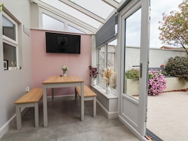 Un invernadero con una mesa, sillas, un televisor y vistas al exterior.