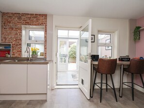 A kitchen with a brick wall, a sink, and a dining area with two chairs and a table.