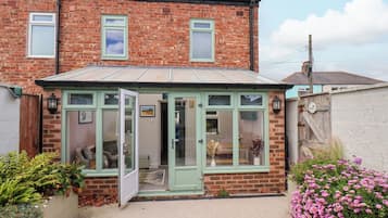 A brick house with a conservatory, a door, and a window.