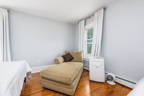 Ein kleines Hotelzimmer mit einem Bett, einer Couch, einer Heizung und einem Fenster.