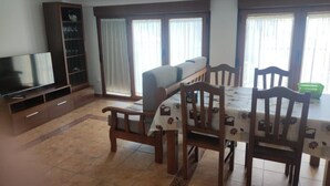 A dining area with a table, chairs, a sofa, a TV, and a cabinet.