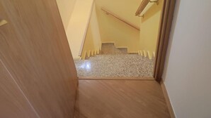A wooden door leading to a carpeted staircase with a handrail.