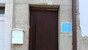 A building entrance with a brown door, a utility box to the left, and a blue sign to the right.