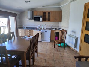 A kitchen with wooden cabinets, a microwave, a dishwasher, and a dining table with chairs.