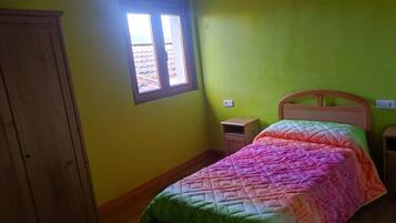 A room with a bed, a window, a wooden wardrobe, and a nightstand.