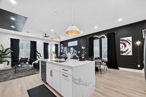 Et moderne køkken med en central ø, sort og hvid indretning og et spiseområde med bord og stole.