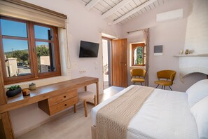 Un dormitorio con cama, escritorio, dos sillas, televisor y ventana.