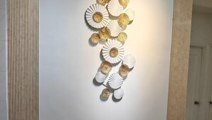 Ein Essbereich mit einem runden Tisch, Stühlen und einem an der Wand befestigten dekorativen Element.