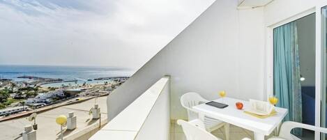 Un balcone con tavolo e sedie, vista sulla costa.