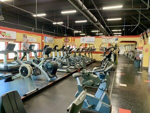 A gym with multiple treadmills and exercise machines, a clean floor, and various signs on the walls. - Royale Palms 1707 Elegant Oceanview w/Pool & Beach (Myrtle Beach)