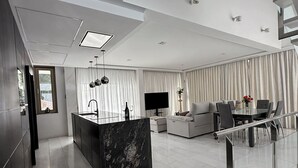 Ein modernes Interieur mit Kücheninsel, Essbereich und Treppe.
