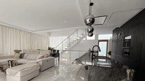 Ein modernes Wohnzimmer mit Sofa, Essbereich, einer Küche mit Marmorinsel und einer Treppe.