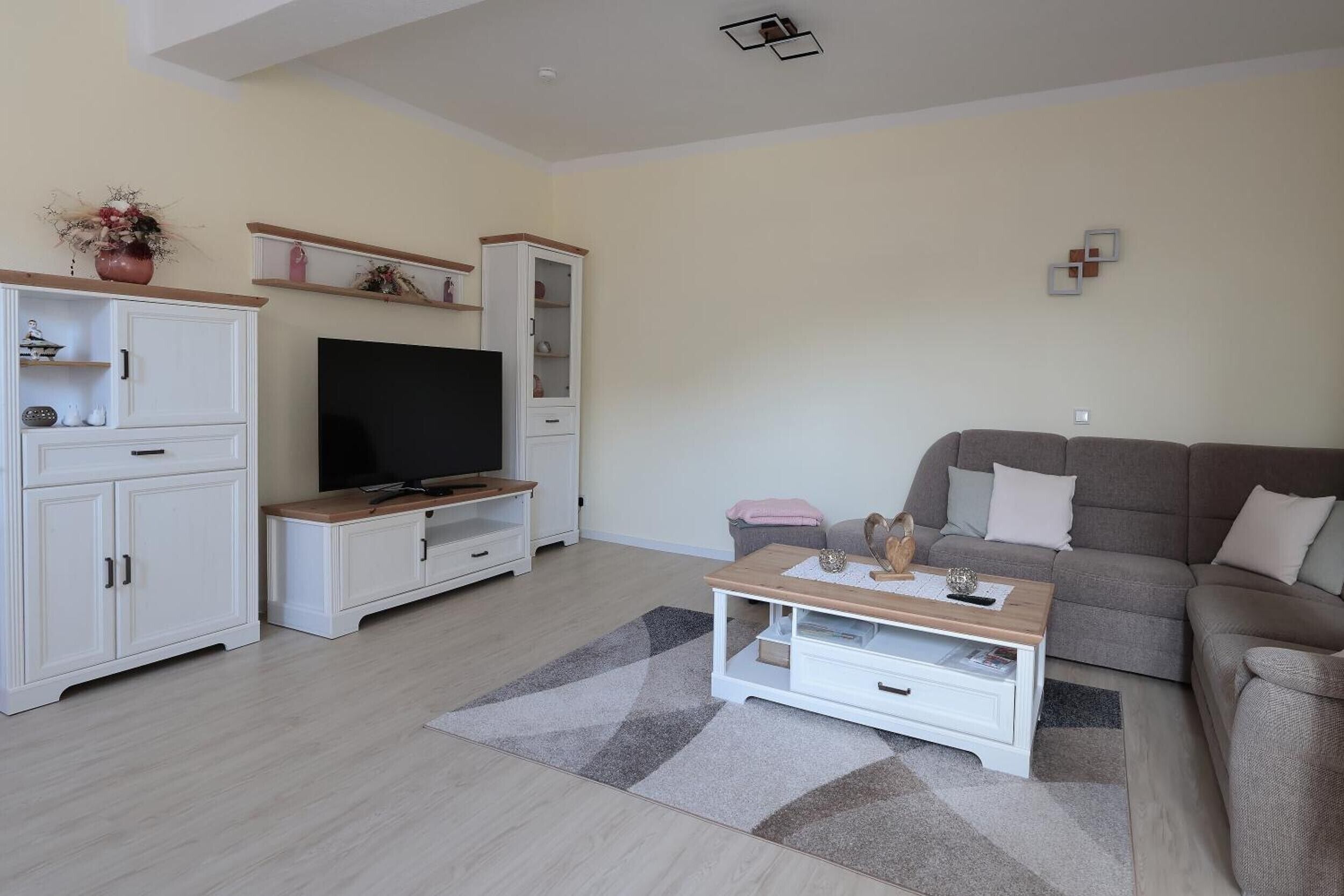 Una sala de estar con televisor, sofá, mesa de centro y muebles de almacenaje.